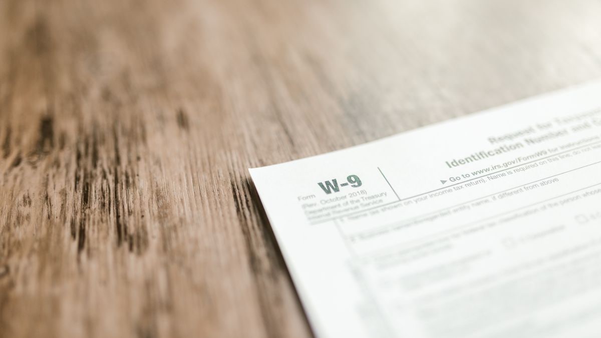 A close-up of a W-9 tax form placed on a wooden desk, emphasizing paperwork and finance.
